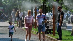 Люди захищаються від спеки під вуличною системою охолоджувального туману