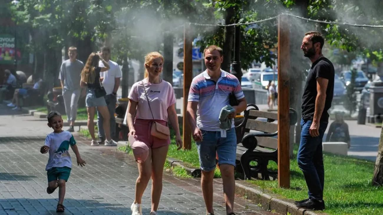 Люди захищаються від спеки під вуличною системою охолоджувального туману