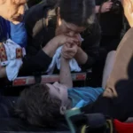 Мать держит руку 6-летнего сына на носилках после спасения из-под завалов во Львове