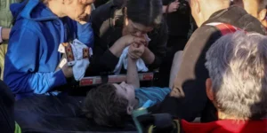 Мать держит руку 6-летнего сына на носилках после спасения из-под завалов во Львове