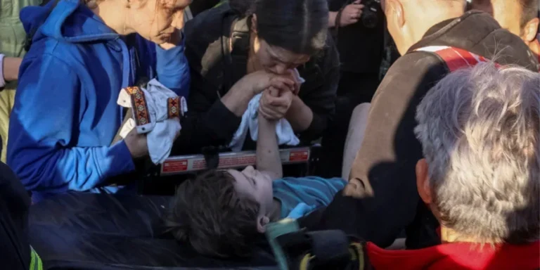 Мать держит руку 6-летнего сына на носилках после спасения из-под завалов во Львове