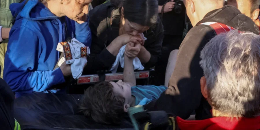 Мать держит руку 6-летнего сына на носилках после спасения из-под завалов во Львове