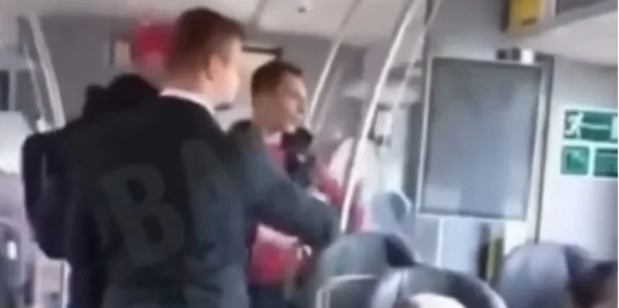 Чоловіки стоять у салоні потяга біля сидінь і аварійних виходів