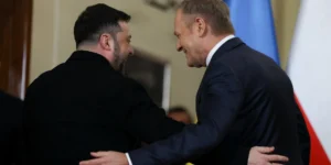Зеленський і Туск обіймаються на тлі прапорів України та Польщі