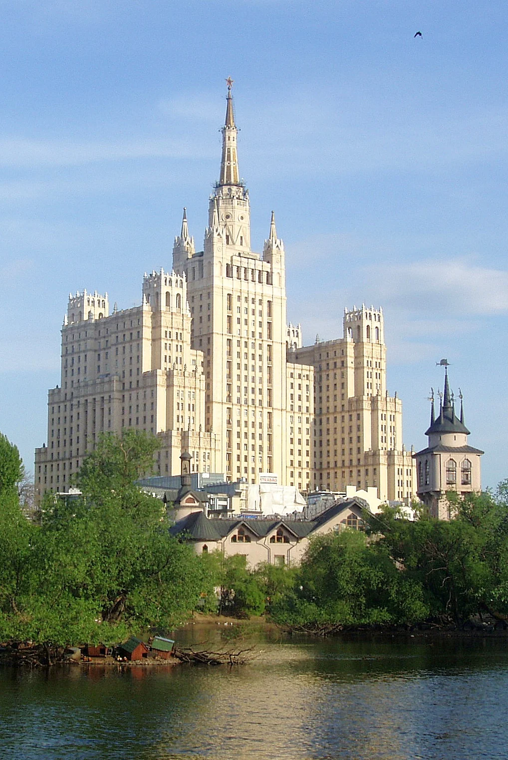 Сталинская высотка на Котельнической набережной в Москве с рекой и деревьями